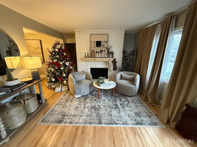 sitting room with hardwood / wood-style floors and a brick fireplace