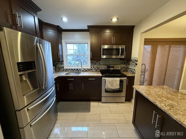 kitchen with sink, crown molding, tasteful backsplash, light stone counters, and stainless steel appliances