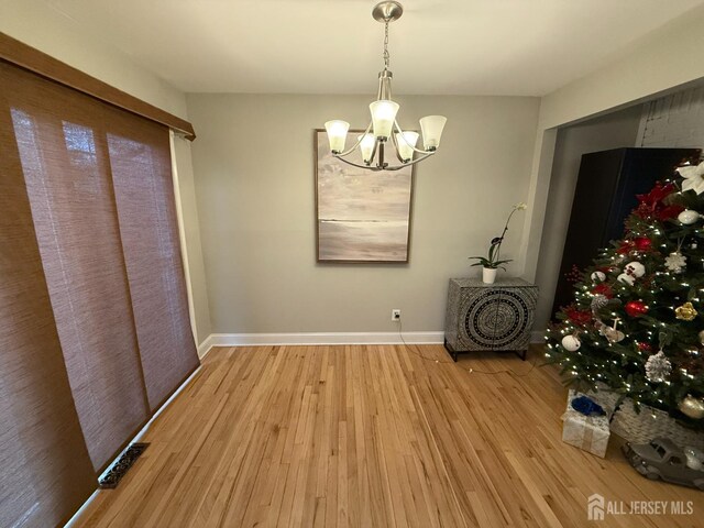 unfurnished dining area featuring wood-type flooring and a chandelier