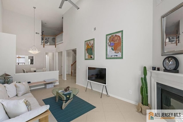 6503 Schindler Dr, South Brunswick, NJ 08852 - living room featuring a high ceiling, ceiling fan, a glass covered fireplace, stairs, and tile patterned floors