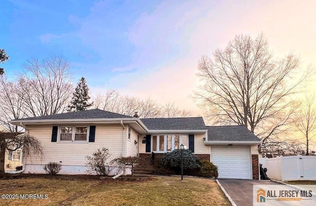 view of front of house featuring driveway, fence, a yard, an attached garage, and brick siding