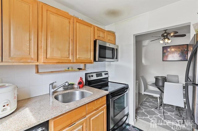 kitchen featuring ceiling fan, decorative backsplash, sink, stainless steel appliances, and light stone counters