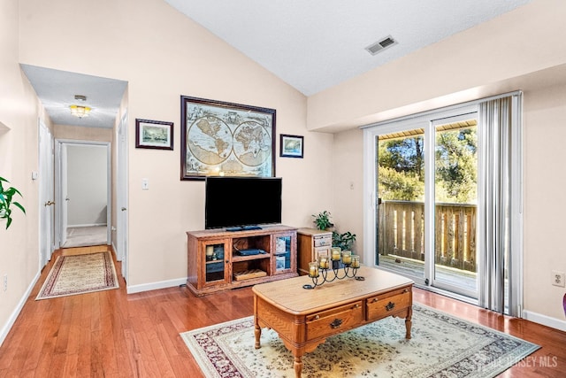 living room featuring visible vents, baseboards, light wood-style floors, and lofted ceiling