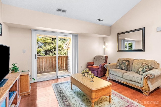 living room with vaulted ceiling, visible vents, and light wood finished floors