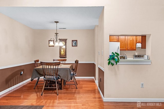 dining room featuring visible vents, baseboards, a notable chandelier, and light wood finished floors