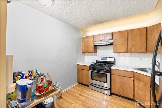 255 Hampshire Ct, Piscataway, NJ 08854 - kitchen with stainless steel gas range oven, under cabinet range hood, a textured ceiling, light wood finished floors, and decorative backsplash