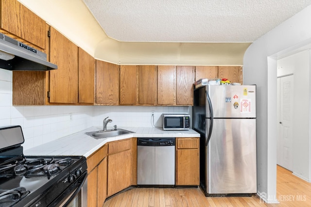 255 Hampshire Ct, Piscataway, NJ 08854 - kitchen with appliances with stainless steel finishes, tile countertops, range hood, light wood-type flooring, and a textured ceiling