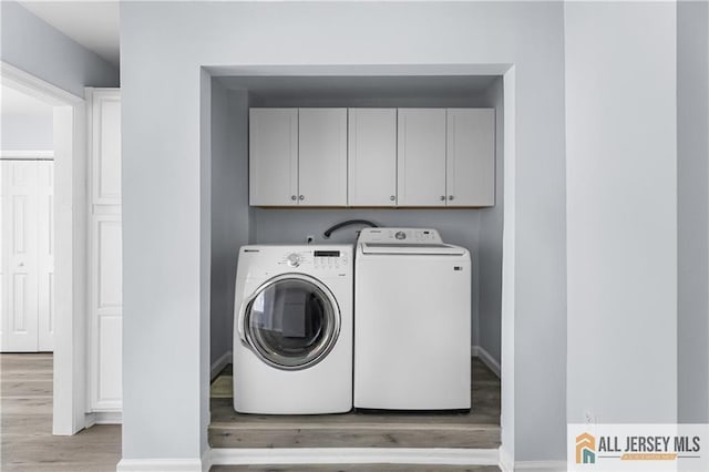 clothes washing area with cabinet space, baseboards, light wood-style floors, and washing machine and clothes dryer