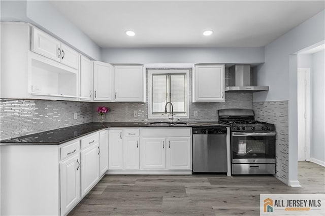 kitchen featuring open shelves, dark countertops, appliances with stainless steel finishes, a sink, and wall chimney range hood