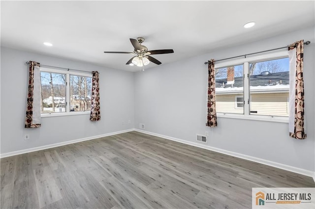 unfurnished room with recessed lighting, wood finished floors, visible vents, and baseboards