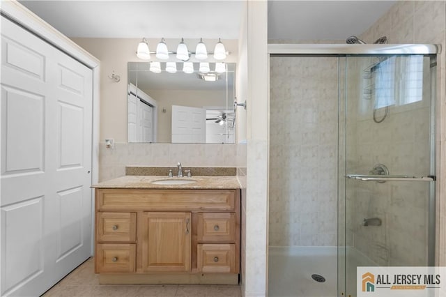 bathroom with a stall shower, tile patterned flooring, ceiling fan, and vanity