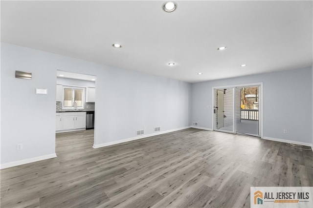 unfurnished living room featuring recessed lighting, visible vents, baseboards, and wood finished floors