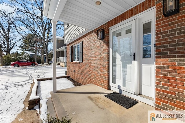 snow covered property entrance with a porch