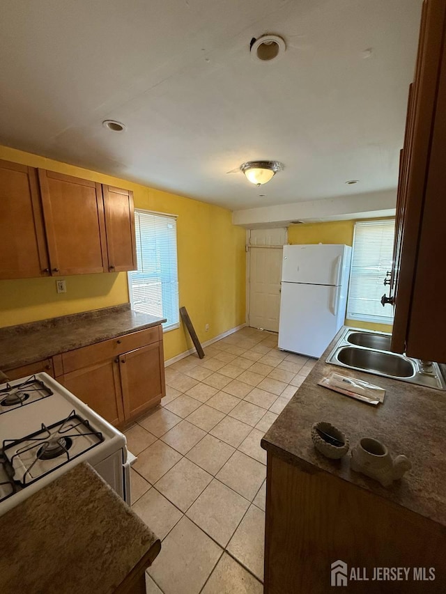 154 Townsend St, New Brunswick, NJ 08901 - kitchen featuring white appliances, dark countertops, light tile patterned flooring, and brown cabinets