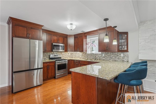 52 State Route 33rd St, Freehold Twp, NJ 07728 - kitchen with appliances with stainless steel finishes, a peninsula, backsplash, a kitchen breakfast bar, and light wood-style floors