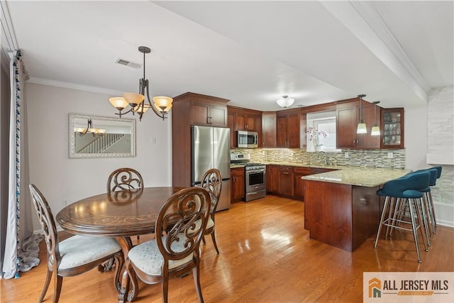 52 State Route 33rd St, Freehold Twp, NJ 07728 - kitchen with appliances with stainless steel finishes, a peninsula, crown molding, decorative backsplash, and light wood-type flooring