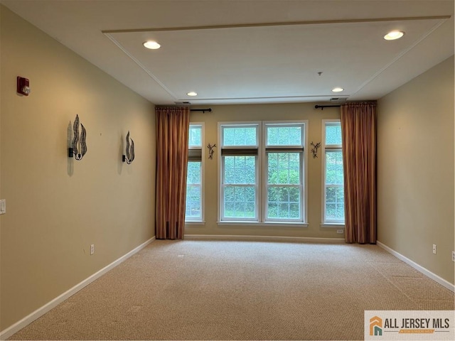 spare room featuring light carpet, recessed lighting, and baseboards