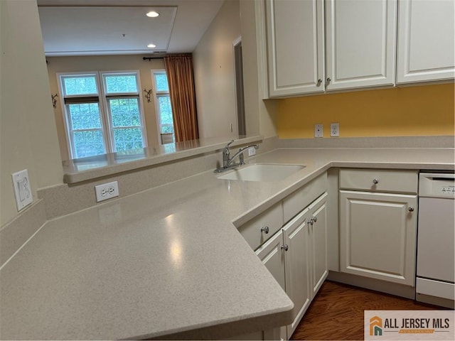 kitchen with white cabinets, white dishwasher, light countertops, a sink, and recessed lighting