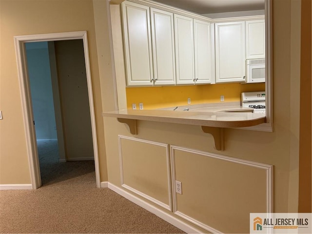 interior space with white appliances, carpet flooring, white cabinetry, and a kitchen breakfast bar