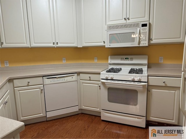 kitchen featuring light countertops, white appliances, white cabinets, and dark wood finished floors