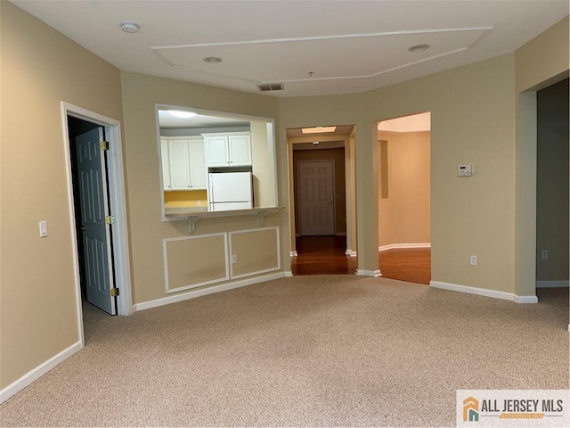 spare room with carpet, visible vents, and baseboards