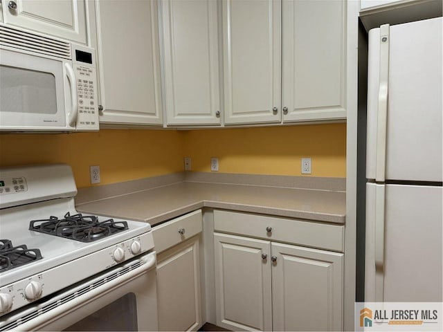 kitchen featuring light countertops, white appliances, and white cabinetry