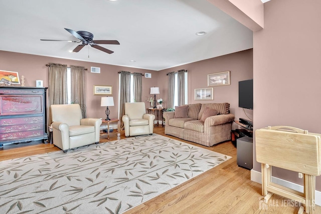 living area with visible vents, ceiling fan, and wood finished floors