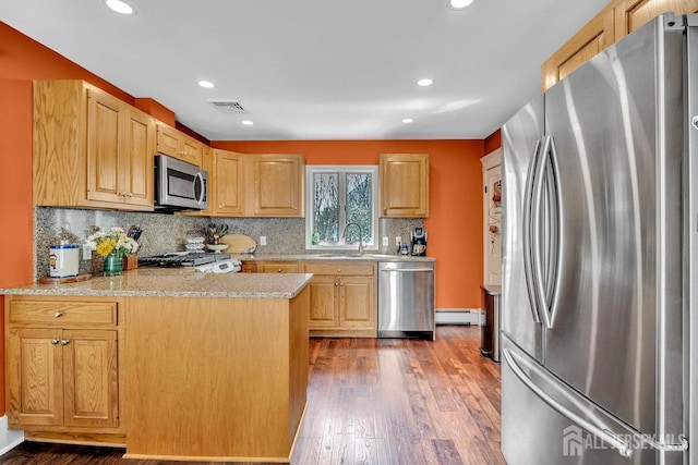 kitchen featuring a sink, stainless steel appliances, visible vents, a peninsula, and wood finished floors