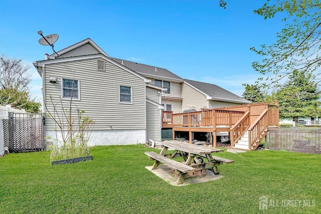 back of property with a lawn, a wooden deck, and fence