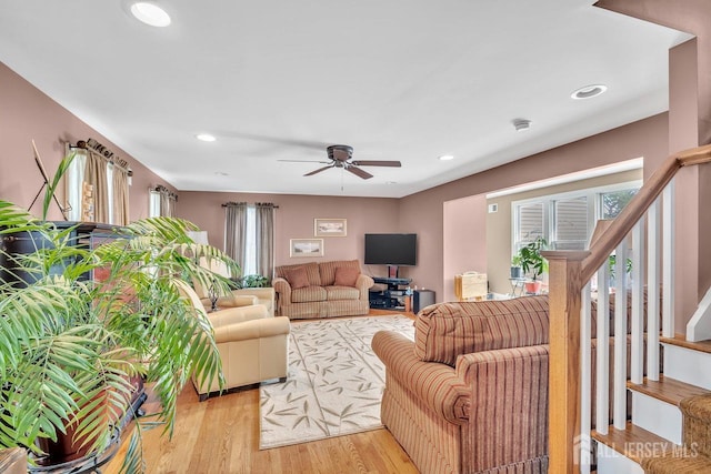 living room with stairway, a healthy amount of sunlight, and light wood-style flooring