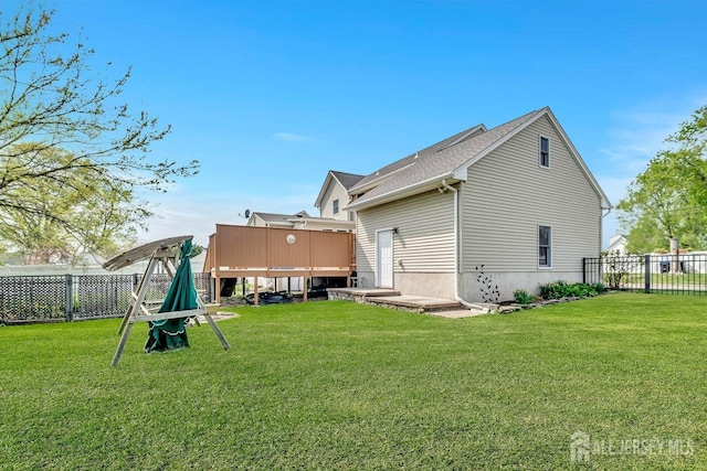 rear view of property with a lawn, a deck, and fence