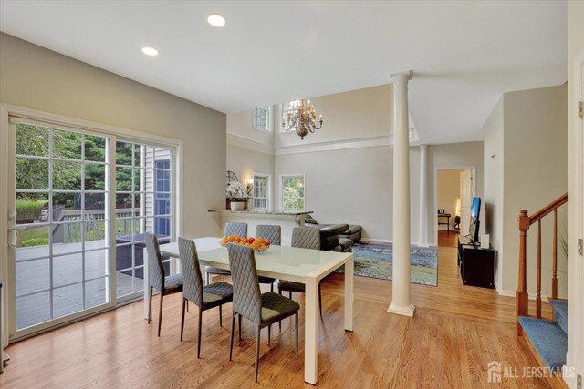 dining space featuring ornate columns, light hardwood / wood-style flooring, and an inviting chandelier