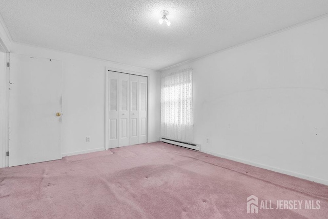unfurnished bedroom featuring a baseboard heating unit, a textured ceiling, carpet, a closet, and baseboards