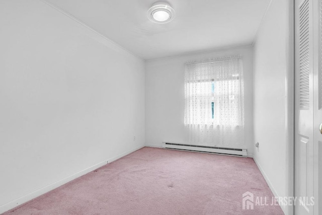 spare room featuring a baseboard heating unit, carpet flooring, and baseboards