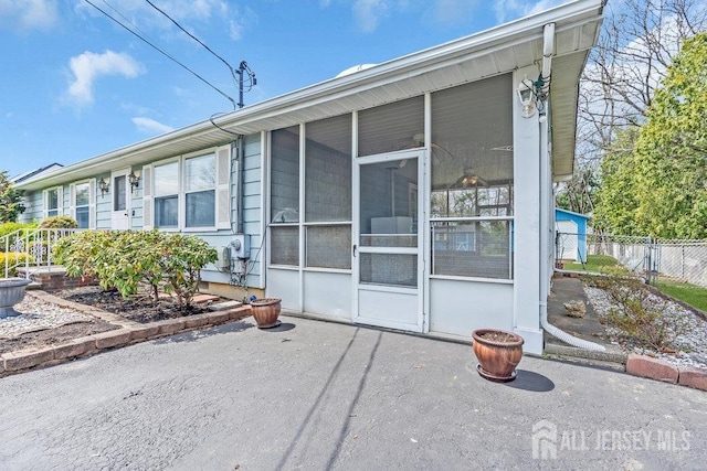 view of front of property featuring a sunroom, fence, and a patio area