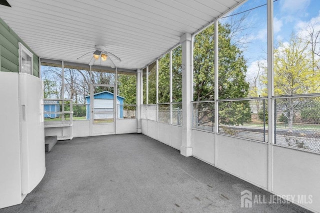 unfurnished sunroom featuring ceiling fan and plenty of natural light