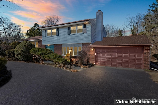 view of front of property with a chimney, brick siding, an attached garage, and driveway