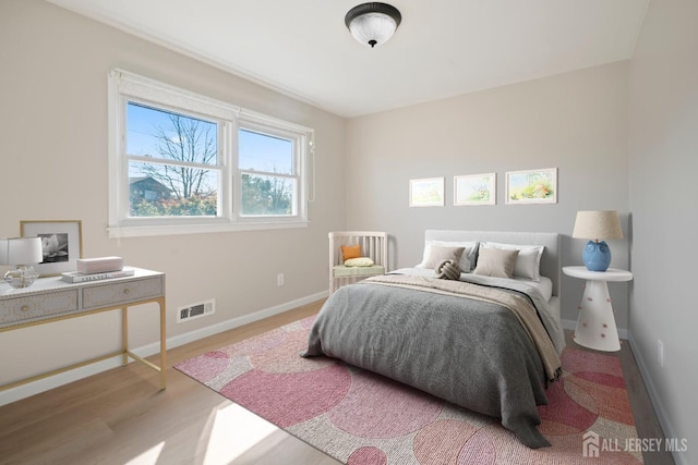 bedroom featuring visible vents, baseboards, and wood finished floors