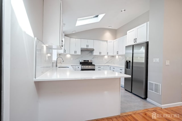 kitchen featuring visible vents, a peninsula, a sink, stainless steel appliances, and under cabinet range hood