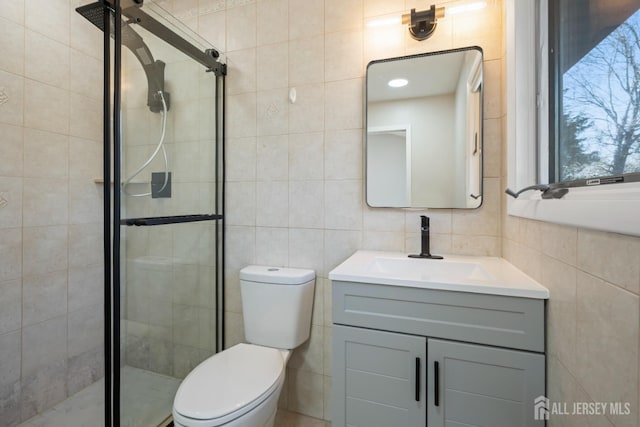 full bath featuring vanity, a shower stall, toilet, and tile walls