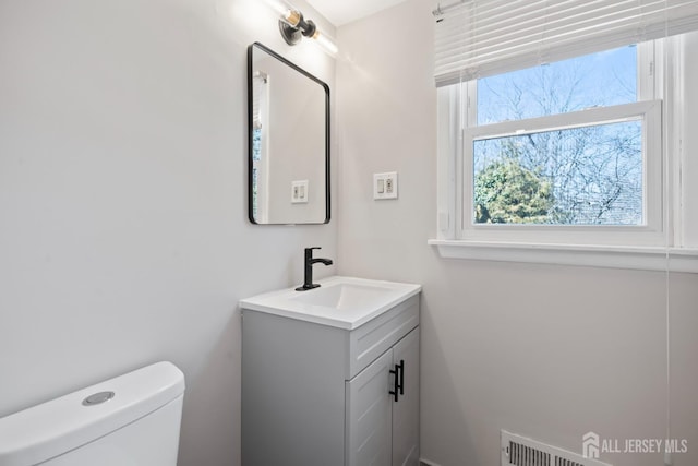 bathroom with vanity, toilet, and visible vents