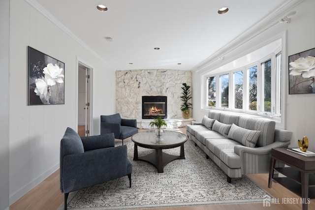 living room featuring a high end fireplace, wood finished floors, baseboards, and ornamental molding