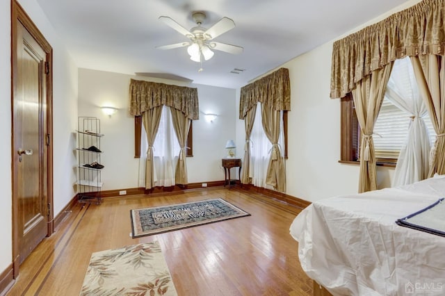 bedroom with visible vents, ceiling fan, baseboards, and wood finished floors