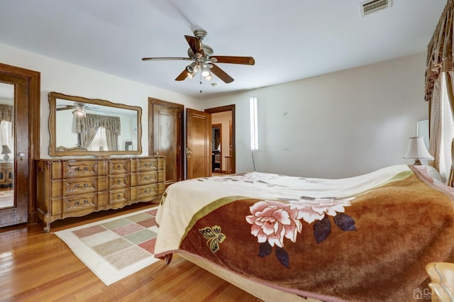 bedroom with a ceiling fan, wood finished floors, and visible vents