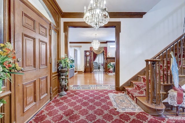 foyer entrance featuring baseboards, a chandelier, stairs, and ornamental molding