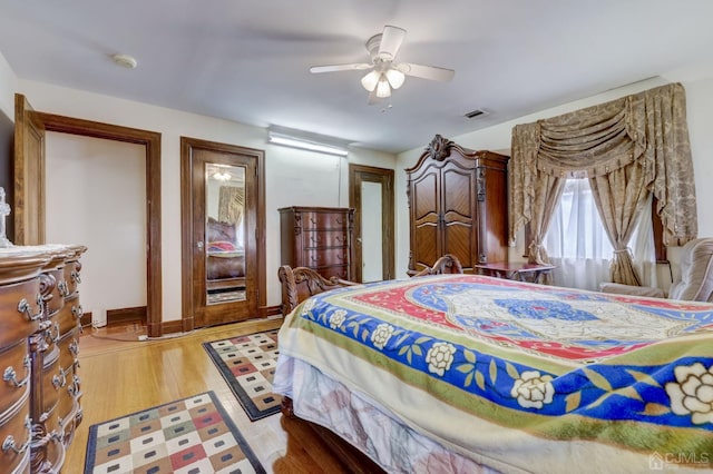 bedroom featuring light wood-type flooring, visible vents, baseboards, and a ceiling fan