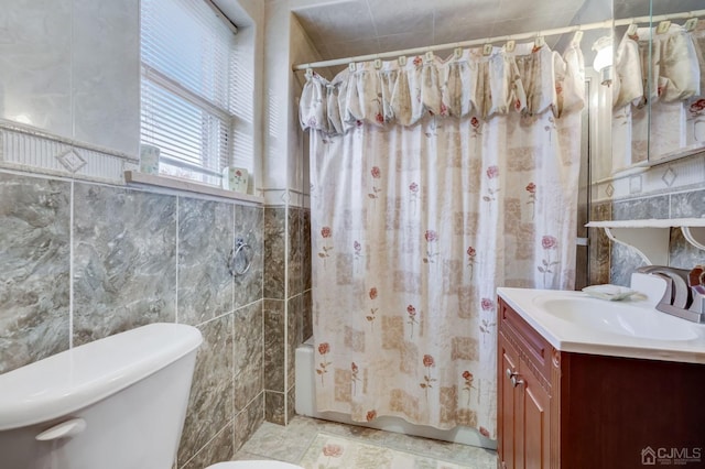 bathroom with tile walls, toilet, vanity, and shower / bath combo