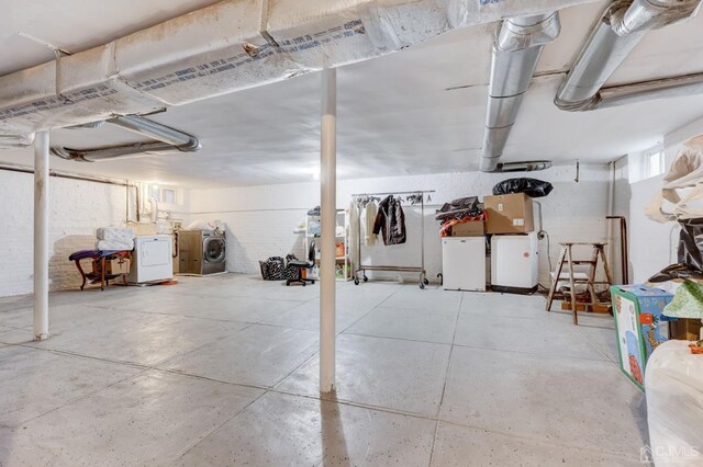 basement featuring separate washer and dryer and brick wall