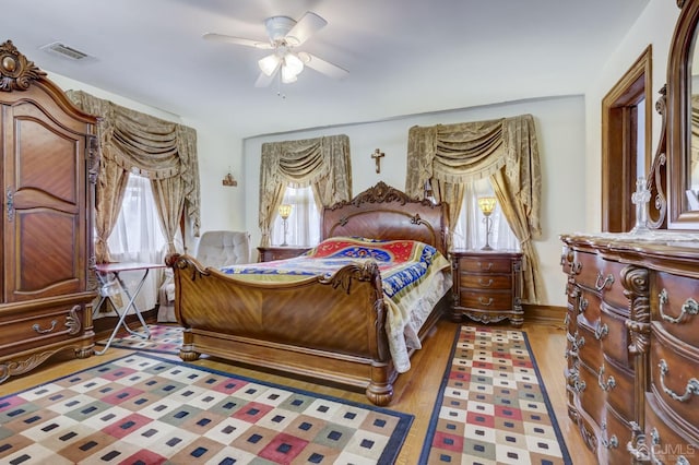 bedroom featuring multiple windows, wood finished floors, visible vents, and ceiling fan