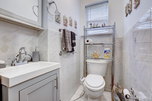 half bath with toilet, tile walls, vanity, and tile patterned flooring